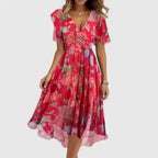 Model wearing a red floral chiffon midi dress with deep V-neckline, flutter sleeves and tie waist