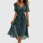 Model in deep green chiffon midi dress with small white floral print, V-neck and tie waist detail