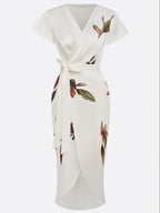 Close-up of the tulip-style skirt hem with front slit, showing the leaf print on the ivory wrap midi dress