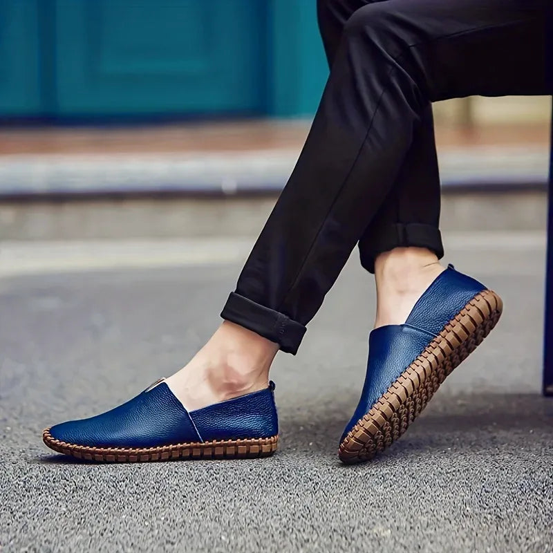 Man wearing royal blue leather loafers with rolled black trousers while seated outdoors