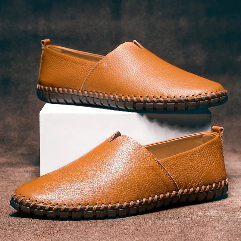 Pair of phoenix brown leather loafers stacked on a white block with visible hand stitched sole