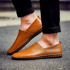 Man wearing phoenix brown leather loafers with rolled black trousers, walking on pavement