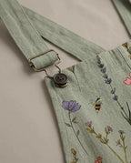 Close-up detail of the antique buckle, button fastening and woven botanical print fabric on the jumpsuit strap