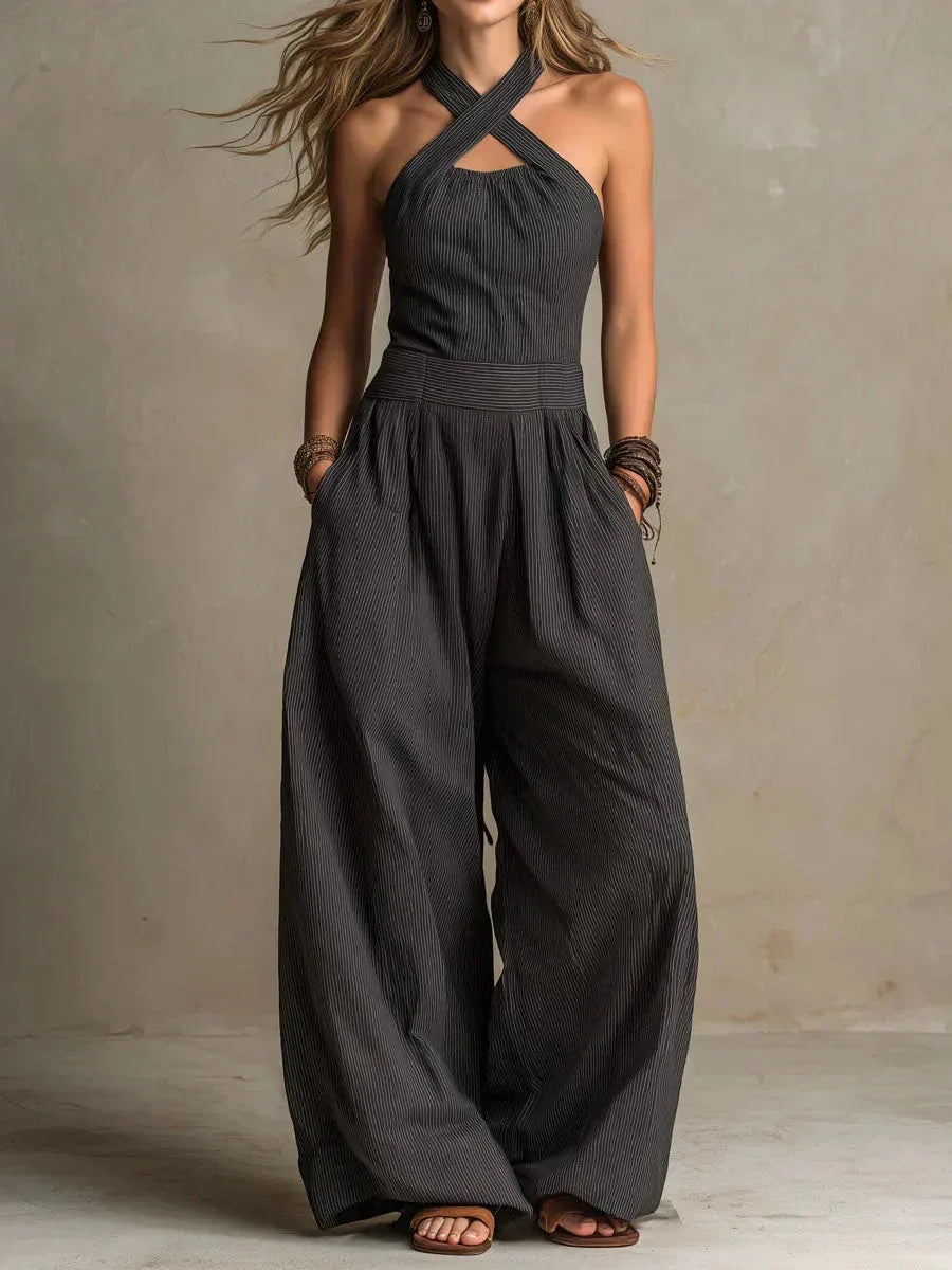 Front view of model in a black pinstripe halter jumpsuit with crossed neckline and wide palazzo-style legs
