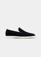 Side profile of a black suede loafer with white apron-toe stitching and a clean off-white sole