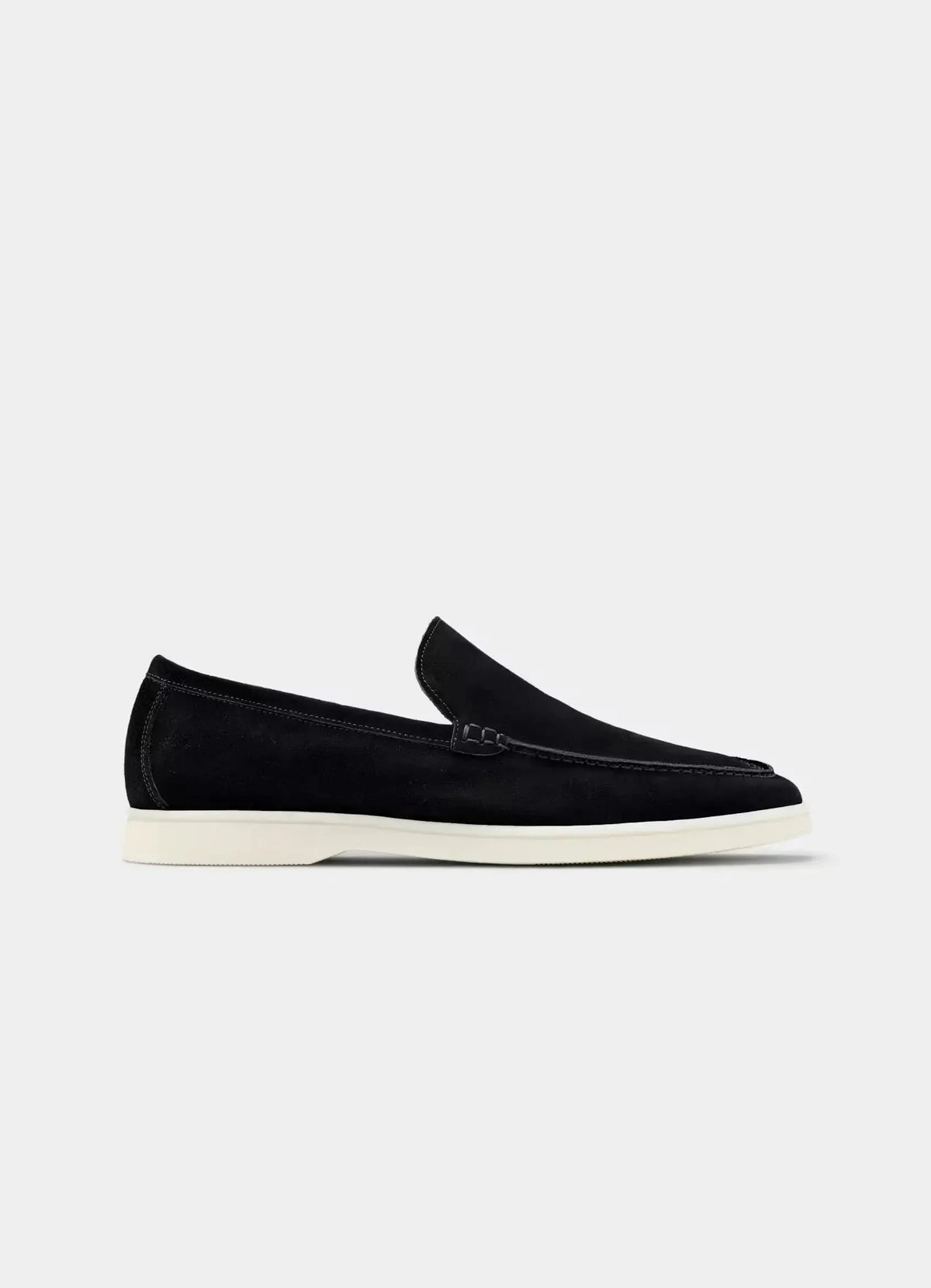 Side profile of a black suede loafer with white apron-toe stitching and a clean off-white sole