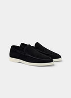 Angled pair shot of black suede loafers on a plain background highlighting the low-profile silhouette