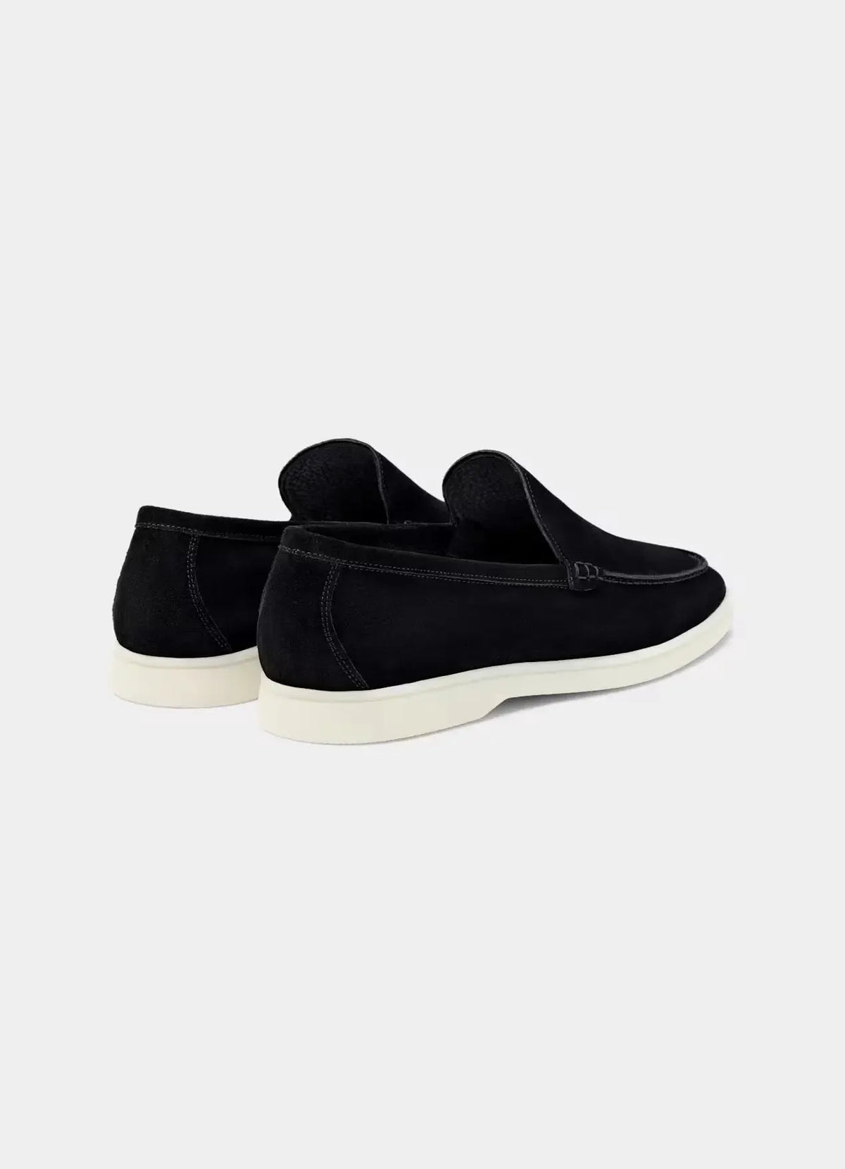 Three-quarter rear view of a pair of black suede loafers showing the heel counter and white midsole