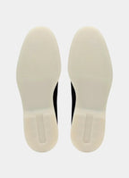 Top-down view of the loafers' off-white rubber soles, showing the tread pattern and heel grip