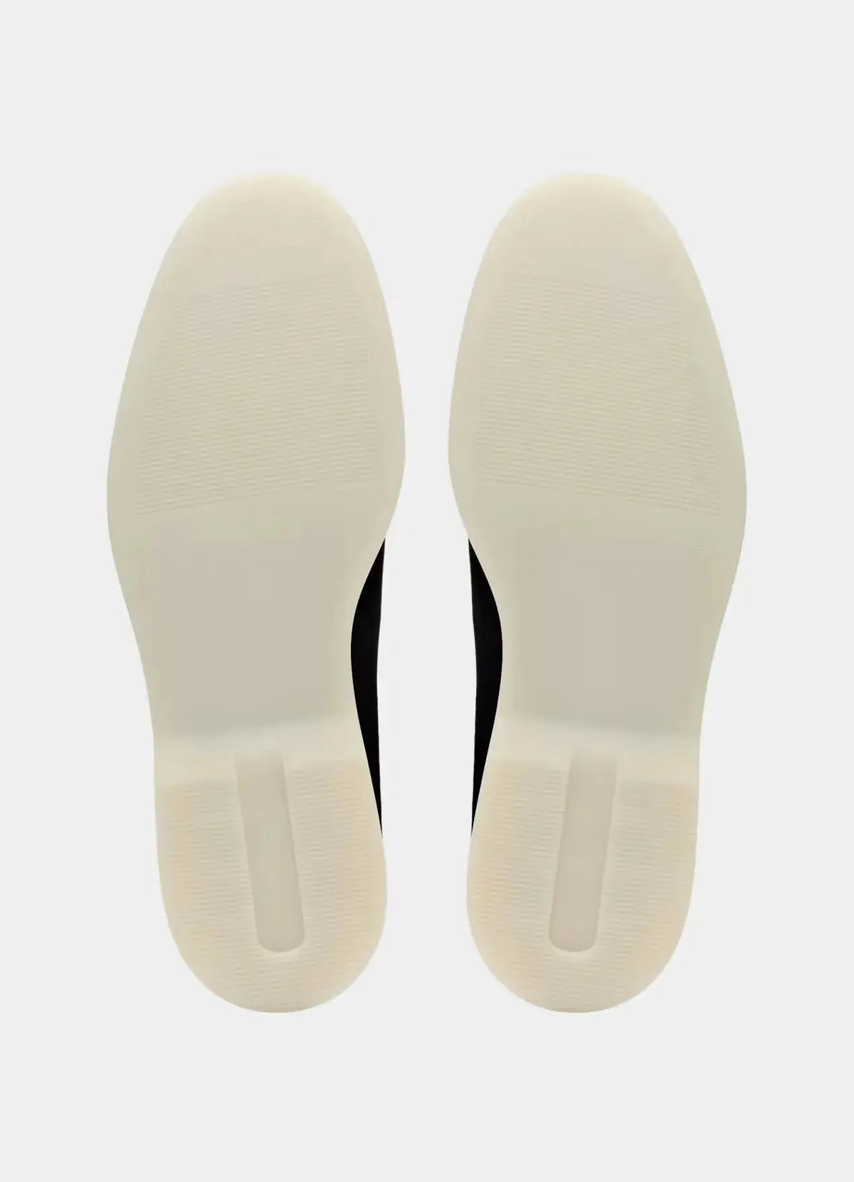 Top-down view of the loafers' off-white rubber soles, showing the tread pattern and heel grip