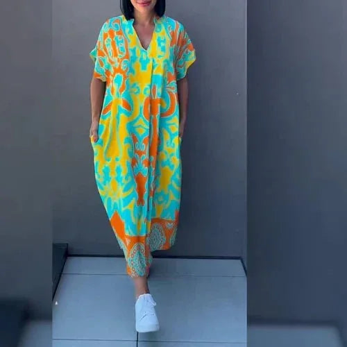 Model in a yellow and turquoise abstract print kaftan midi dress with short cuffed sleeves and V-neckline