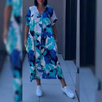 Woman wearing a blue and white floral leaf print kaftan dress with a relaxed silhouette and side pockets