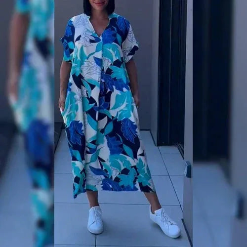 Woman wearing a blue and white floral leaf print kaftan dress with a relaxed silhouette and side pockets