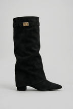 Side profile of a black suede-look knee-high boot with slouchy shaft, pointed toe and gold turn-lock buckle strap