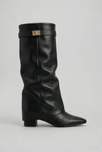 Side view of a black leather-look knee-high boot with block heel, pointed toe and gold buckle detail at the cuff