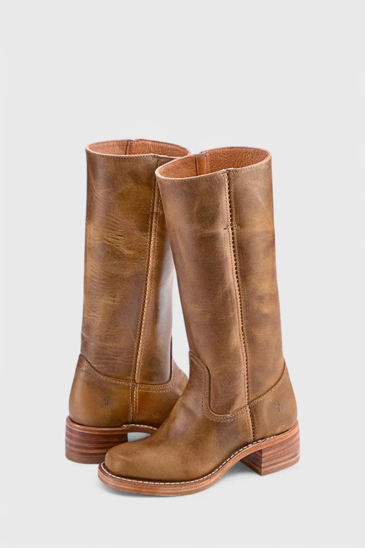 Front view of weathered tan leather knee-high boots with visible natural grain and stacked heel