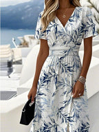 Close-up view of the V-neck wrap bodice and ruched waistband on the blue leaf-print midi dress.