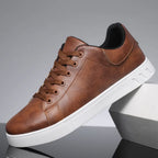 Side profile of brown leather sneaker propped on a white box, highlighting stitched panels and white sole