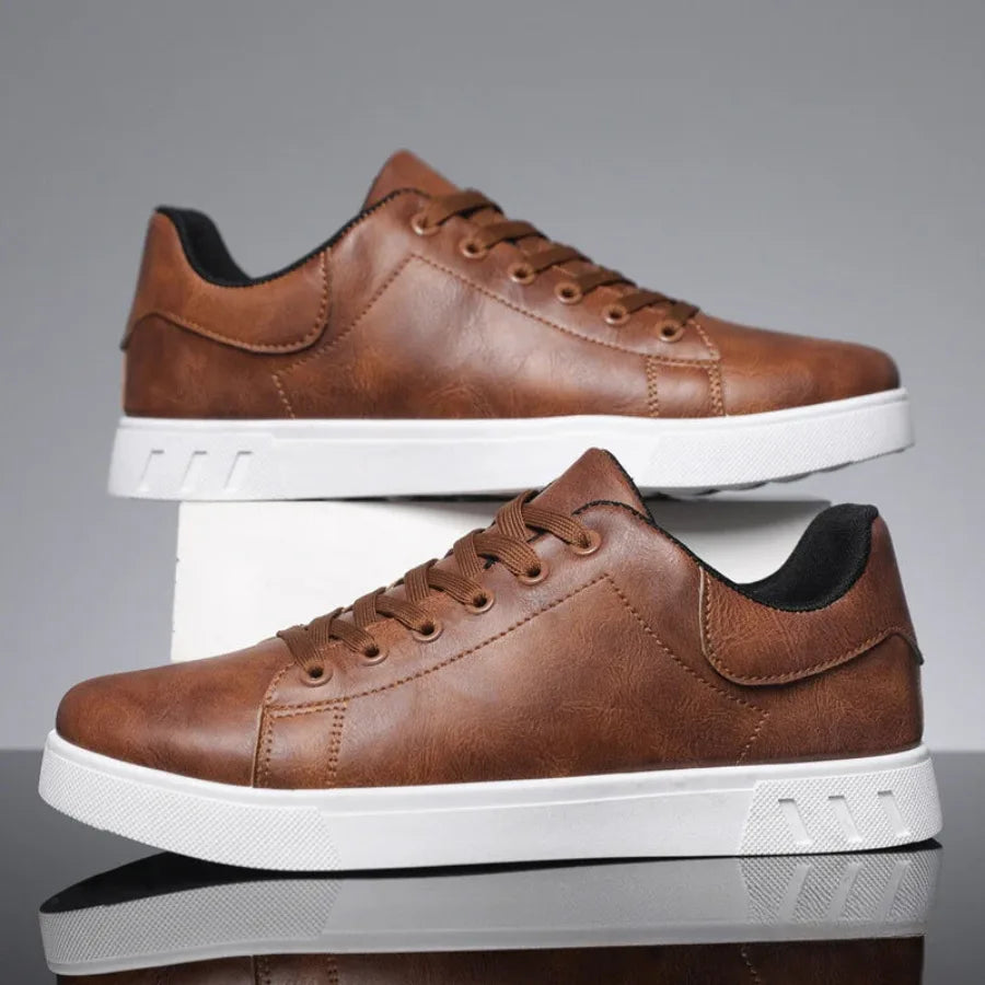 Pair of brown leather sneakers stacked on a white box, showing matching stitching and white soles