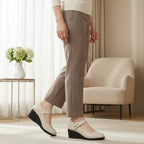 Side view of a woman walking in beige leather Mary Jane wedge shoes with a diamante strap buckle