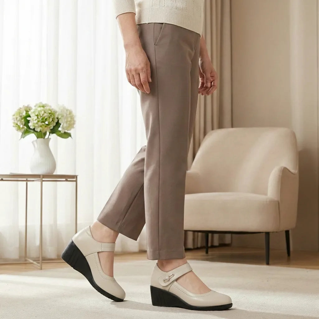 Side view of a woman walking in beige leather Mary Jane wedge shoes with a diamante strap buckle