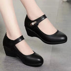 Front angle of black leather Mary Jane wedge shoes highlighting the round toe and low wedge heel