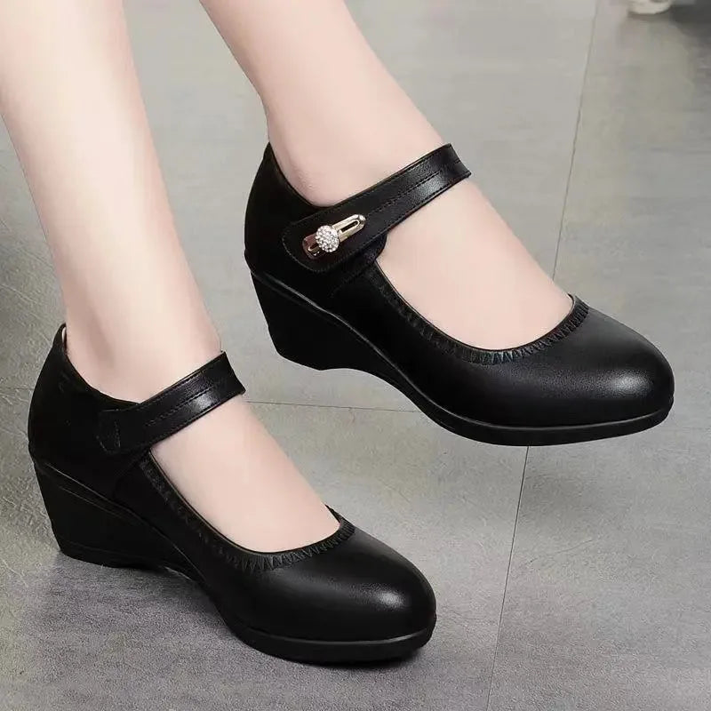 Front angle of black leather Mary Jane wedge shoes highlighting the round toe and low wedge heel
