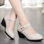 Close-up of beige leather Mary Jane wedge shoes worn on bare feet showing the stacked wedge sole