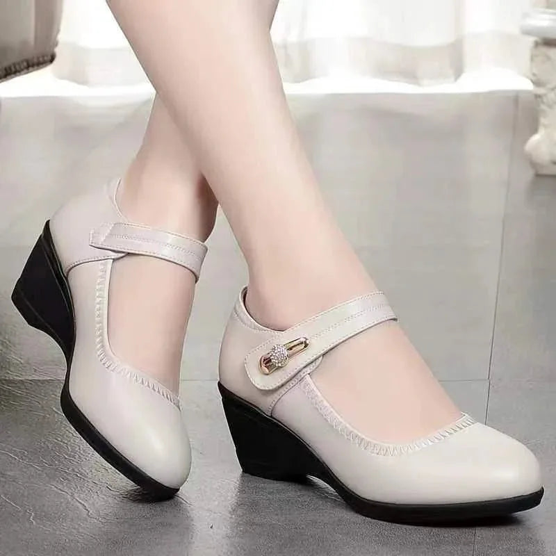 Close-up of beige leather Mary Jane wedge shoes worn on bare feet showing the stacked wedge sole
