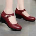 Angled view of burgundy leather Mary Jane wedge shoes with contrast black wedge sole on a tiled floor