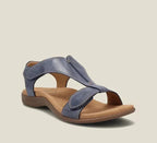 Navy blue leather sandal with crossover T-strap design, adjustable hook-and-loop straps and tan cushioned footbed, three-quarter view.