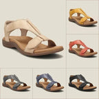 Flat lay grid of six colourways including beige, yellow, coral, navy, grey and black leather T-strap sandals with tan soles.