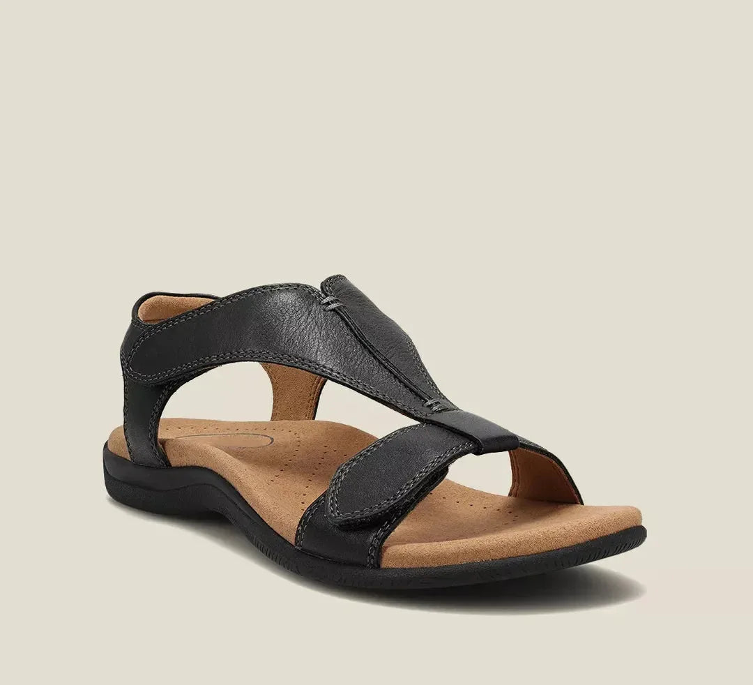 Black leather T-strap sandal with adjustable touch-fasten straps, stitched detailing and padded tan insole, three-quarter angle.