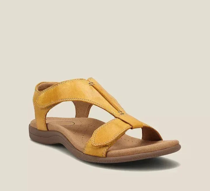 Mustard yellow leather sandal featuring crossover straps, reinforced stitching and a cushioned tan footbed, side angle view.