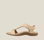 Beige leather sandal shown in profile, highlighting the curved T-strap silhouette and low stacked heel with contrast sole.