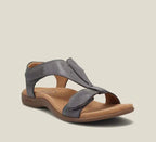 Charcoal grey leather sandal with adjustable crossover straps, branded footbed and chunky tan outsole, three-quarter view.