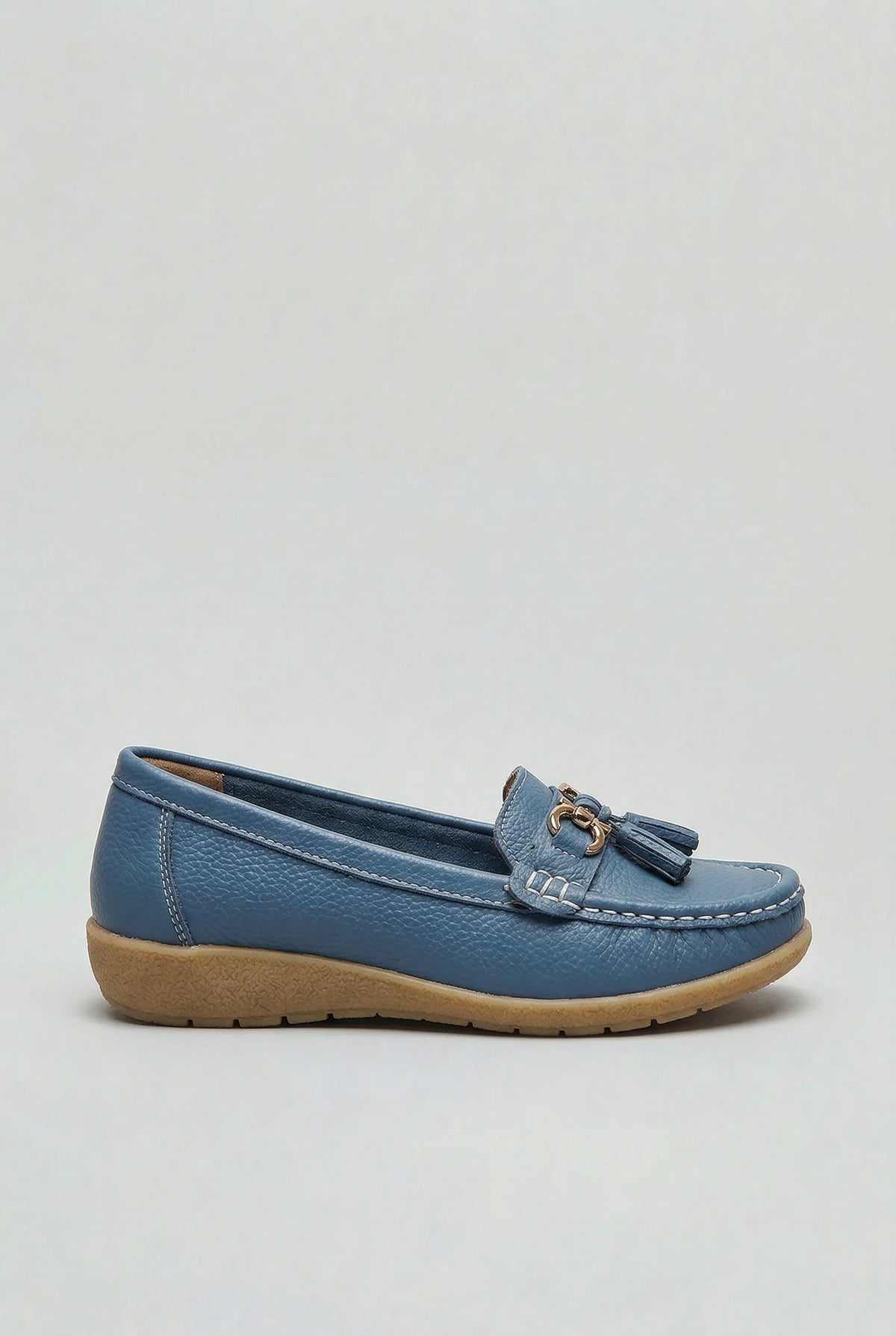 Side profile of a dusty blue leather loafer with gold-tone tassel trim and stitched moc-toe detailing