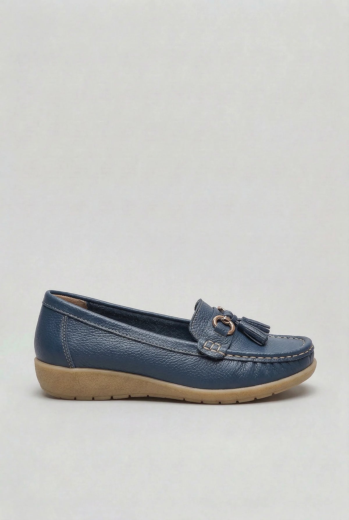 Side profile of a navy leather loafer with gold-tone tassel trim and a cushioned wedge sole