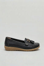 Side profile of a black leather loafer with tassel detailing and a textured rubber wedge outsole