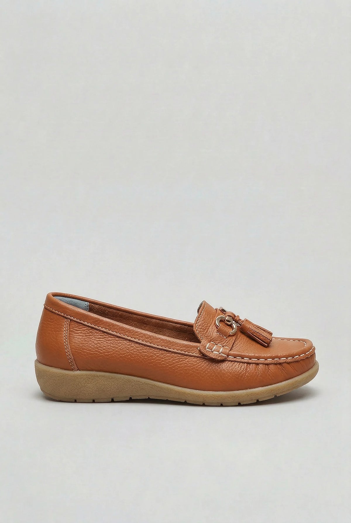 Side profile of a tan leather loafer with gold-tone tassel trim and contrast topstitching