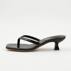 Side profile of a black leather thong-strap sandal with a square toe and curved kitten heel
