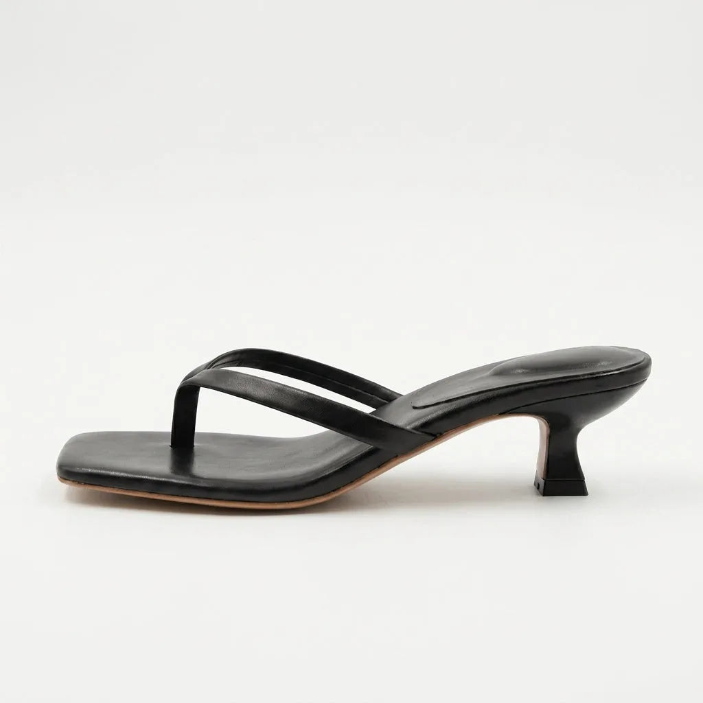 Side profile of a black leather thong-strap sandal with a square toe and curved kitten heel