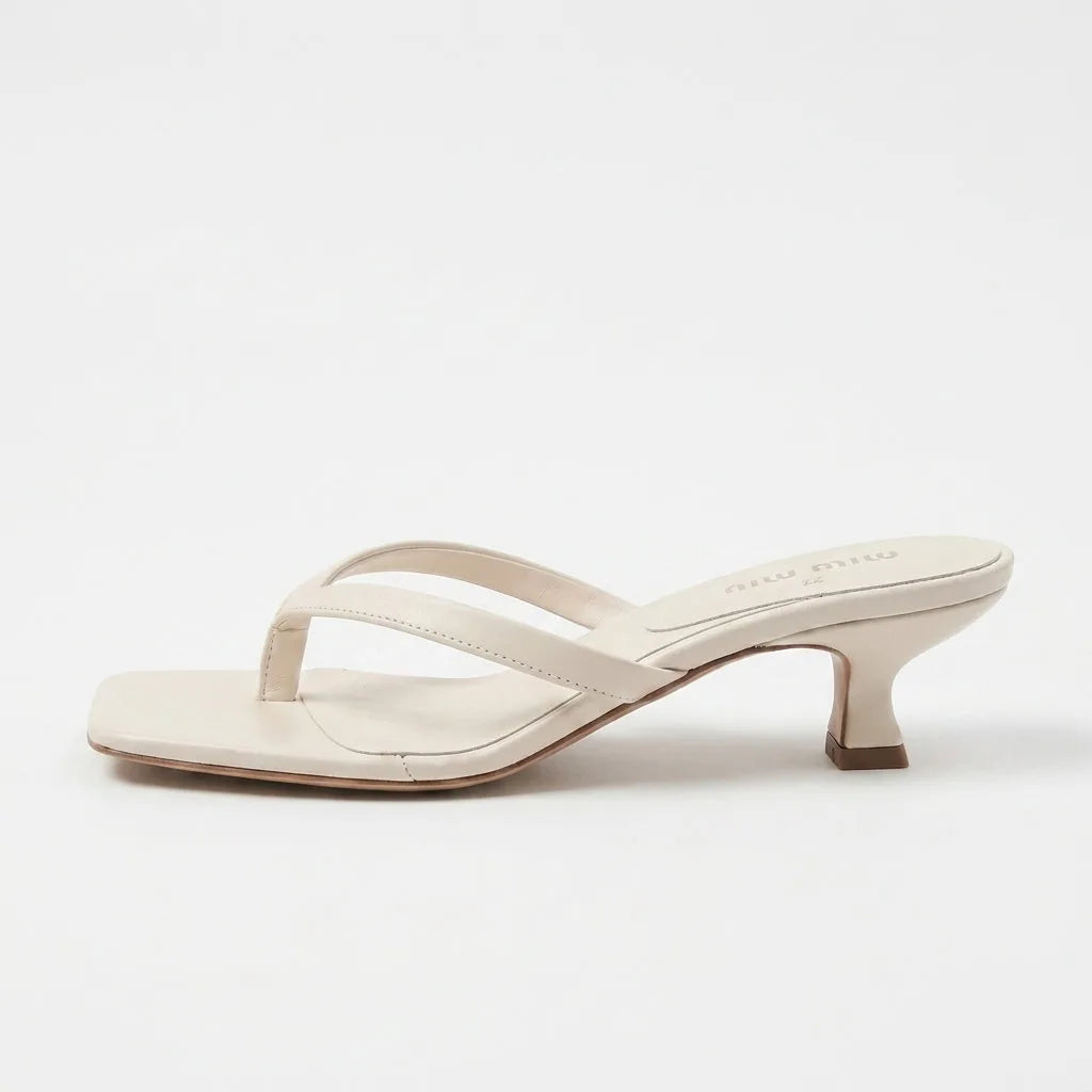 Beige leather thong sandal with a padded footbed and sculpted spool-style kitten heel, side angle