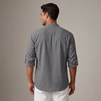 Back view of the grey linen shirt showing the relaxed fit, curved hem and rolled sleeve tabs with button detail.