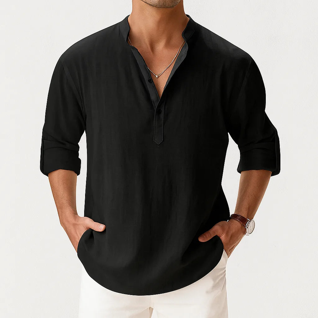 Cropped front view of a man wearing the shirt in black with a layered silver chain necklace and rolled sleeves.
