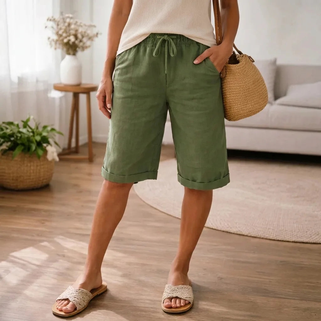 Army green linen Bermuda shorts with turned-up cuffs and drawstring waist, shown with a crochet handbag and sandals