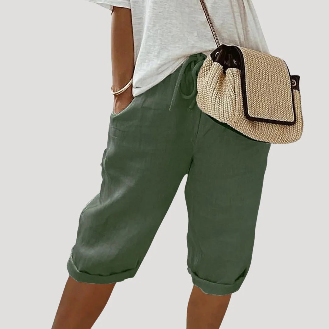 Green linen bermuda shorts with turned-up hems styled with a casual oversized tee