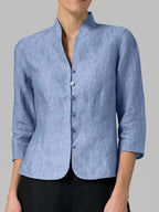 Close-up front view of a woman wearing a light blue heathered linen blazer with mandarin collar and button closure