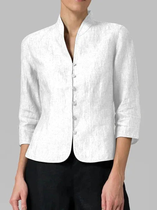 Close-up of a white linen blazer worn open at the collar, showing the mandarin collar and curved hem