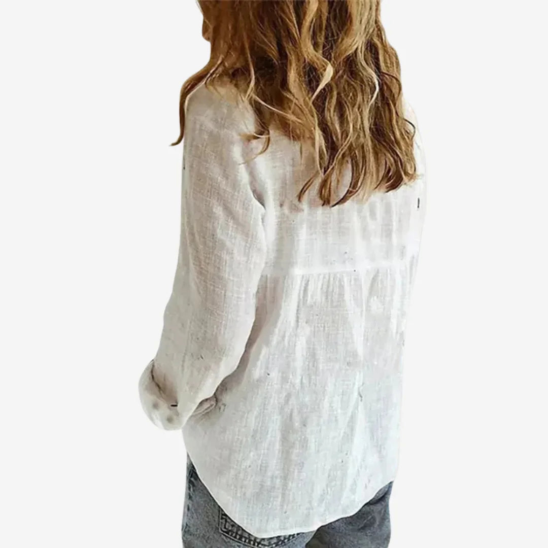 Side back view of a white linen blouse showing the loose fit, rolled sleeve cuff and curved hemline